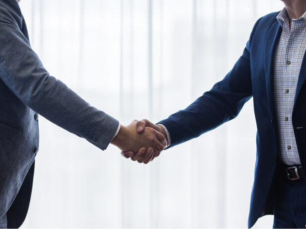 Two business people wearing suits shaking hands.