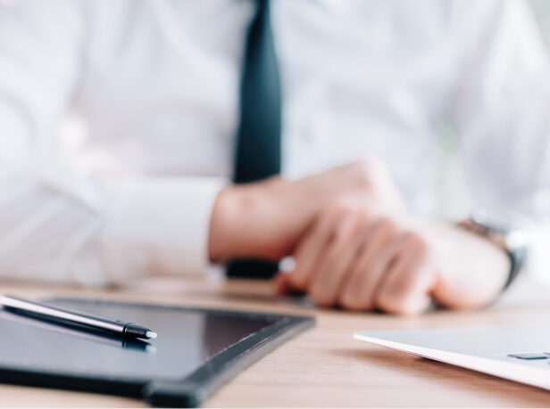 A business person sitting at a desk with a tablet, stylus, and laptop.