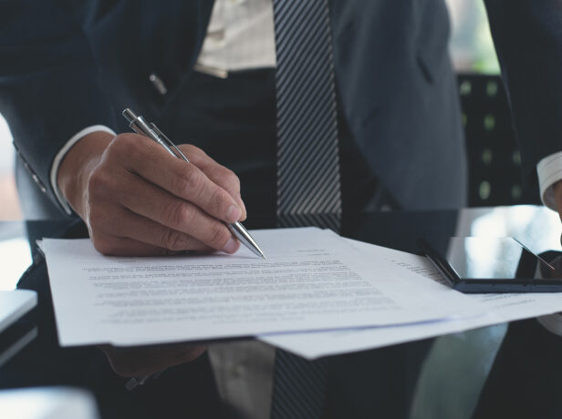 A business person drafting up a contract in a formal setting.