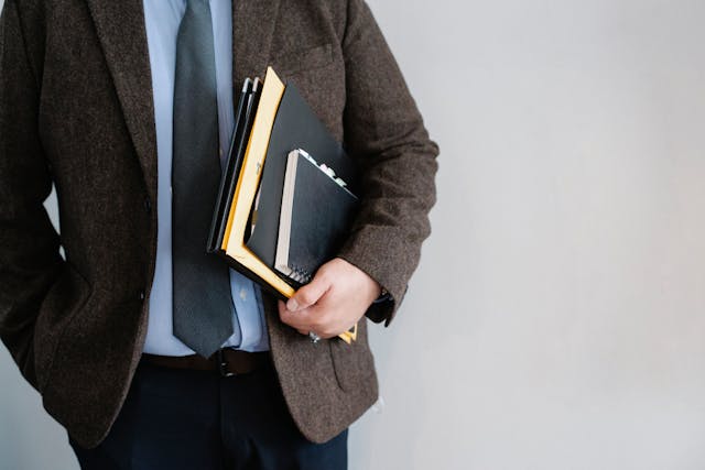 man holding notebooks at side